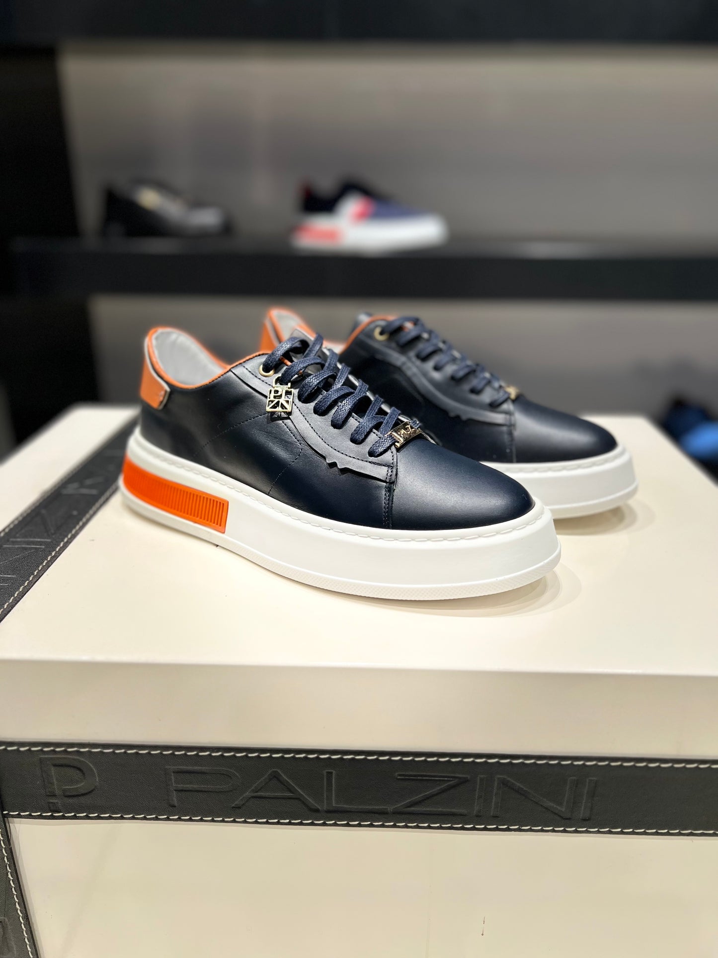 “ASTRAL” LOW-TOP SNEAKERS IN NAVY LEATHER WITH ORANGE ACCENTS.